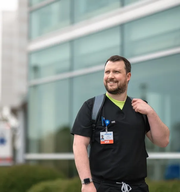 Nurse poses for a photo outside of a hospital.